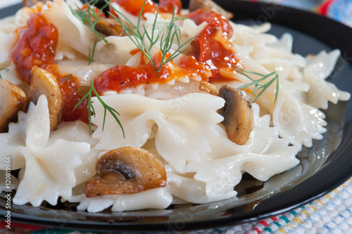 Farfalle Pasta with mushrooms on white plate and tomato sauce