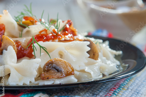 Farfalle Pasta with mushrooms on white plate and tomato sauce