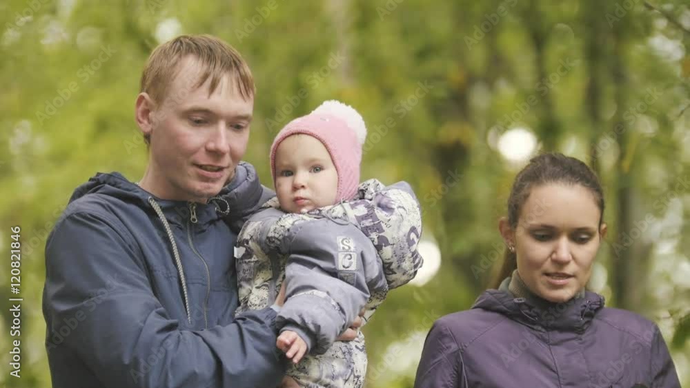 Happy family: Father, Mother and child - little girl in autumn park: walking through the alley with the fallen leaves, close up Happy family: Father, Mother and child - little girl in autumn park: walking through the alley with the fallen leaves, close up