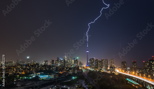 Powerful Lightning bolt strikes over Toronto in a strong, hot, and humid thunderstorm. Stormy night in August, Toronto skyline with weaker flashes of lightning behind the city.