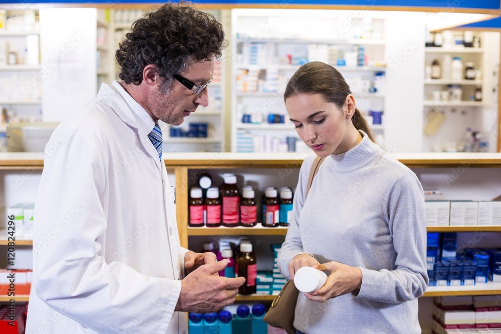Obraz premium Pharmacist assisting the bottle of drug to customer