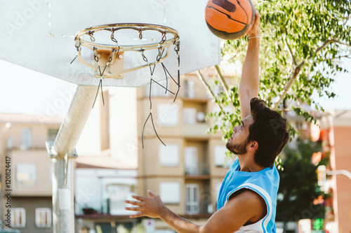 Portrait of handsome young man playing basketball on court.