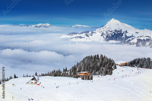 Skier skiing and enjoying beautiful weather on the top of Hahnenkamm. Kitzbüheler Horn peak in the background. Tyrol, Austria