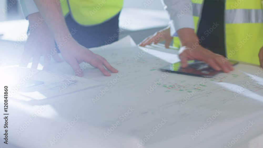 Team of Engineers are Bending over Large Blueprint and Having Conversation, inside Building Under Construction. Shot on RED Cinema Camera in 4K (UHD). Team of Engineers are Bending over Large Blueprint and Having Conversation, inside Building Under Construction. Shot on RED Cinema Camera in 4K (UHD).