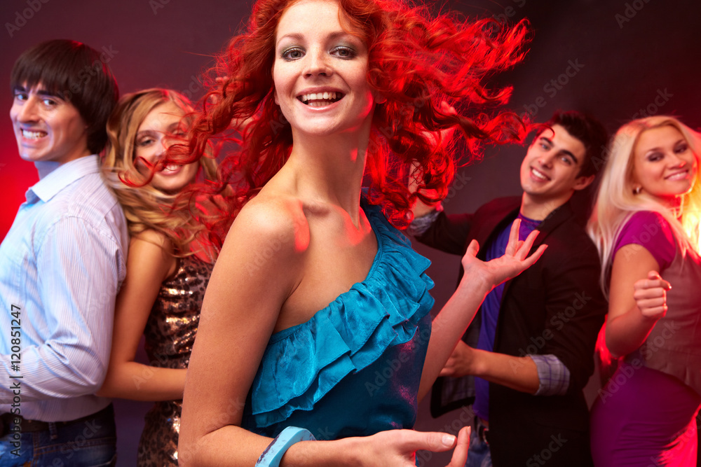 A young girl dancing, looking at camera and smiling against her four friends A young girl dancing, looking at camera and smiling against her four friends