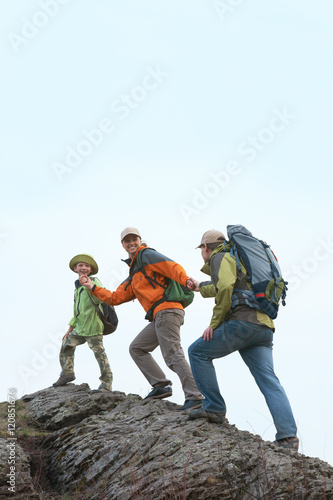 A family of three climbing up the mountain holding hands