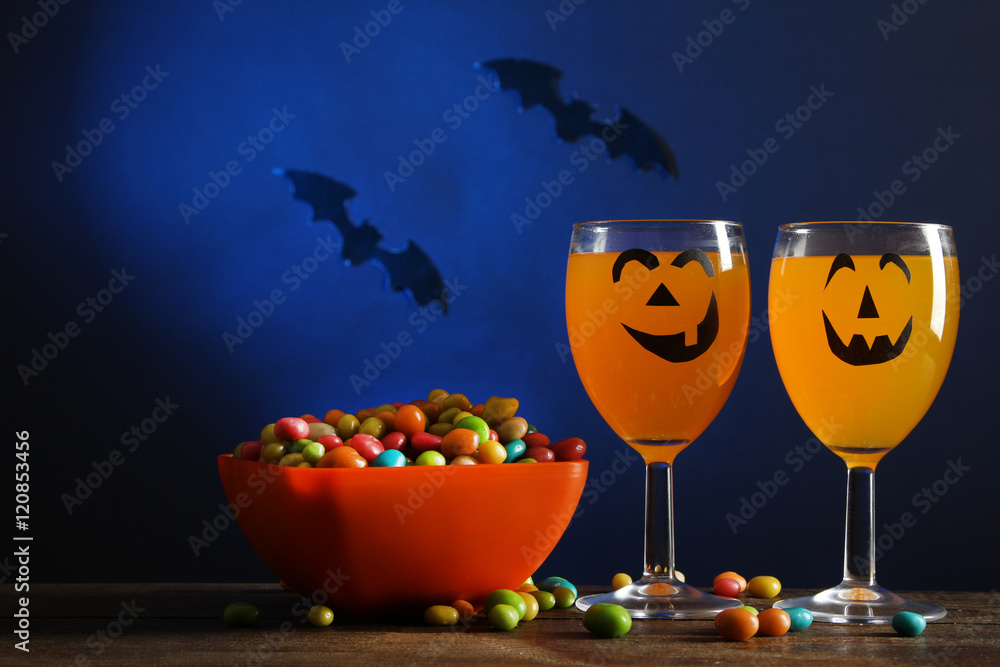 Obraz premium Orange drink with candy on a dark background. Halloween.
