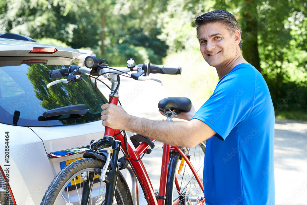 Obraz premium Mature Male Cyclist Taking Mountain Bike From Rack On Car