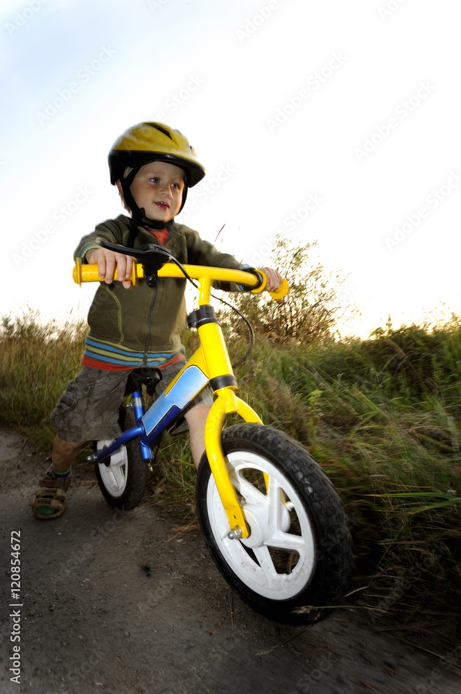 Baby boy riding on his first bike. Bike without pedals. Child learning to ride and balance on his two wheeler bike with no pedals.

