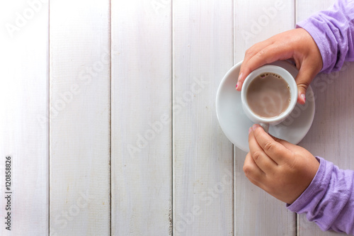 Little Girls Hands Holding Hot Chocolate from Above on White Table with Copy Space