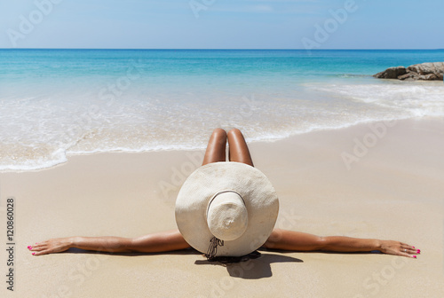 Young pretty slim brunette woman in hat on tropical beach