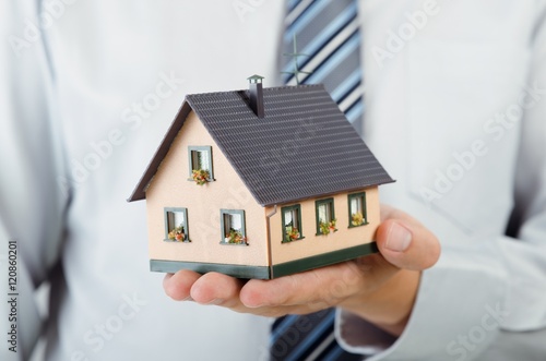 Realtor holding house miniature. Home finance concept