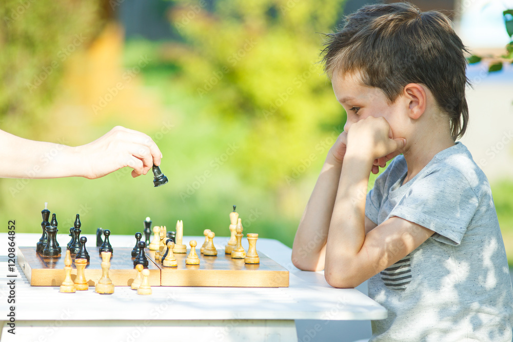 Kids playing chess. Two boys, aged six and eight years, think