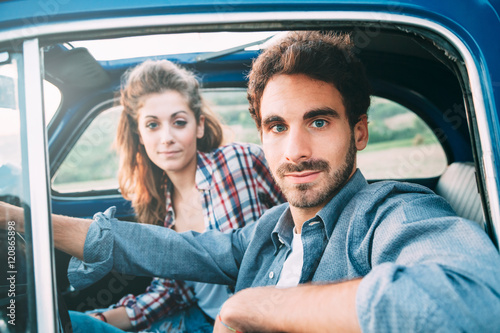 Loving couple in old blue car, young man is driving. Around classic landscape of Tuscany, Italy © loreanto