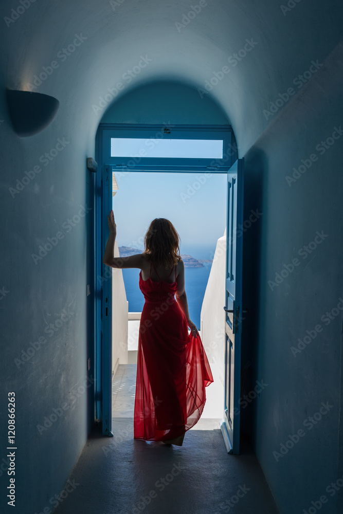 Woman in red dress looks at the sea
