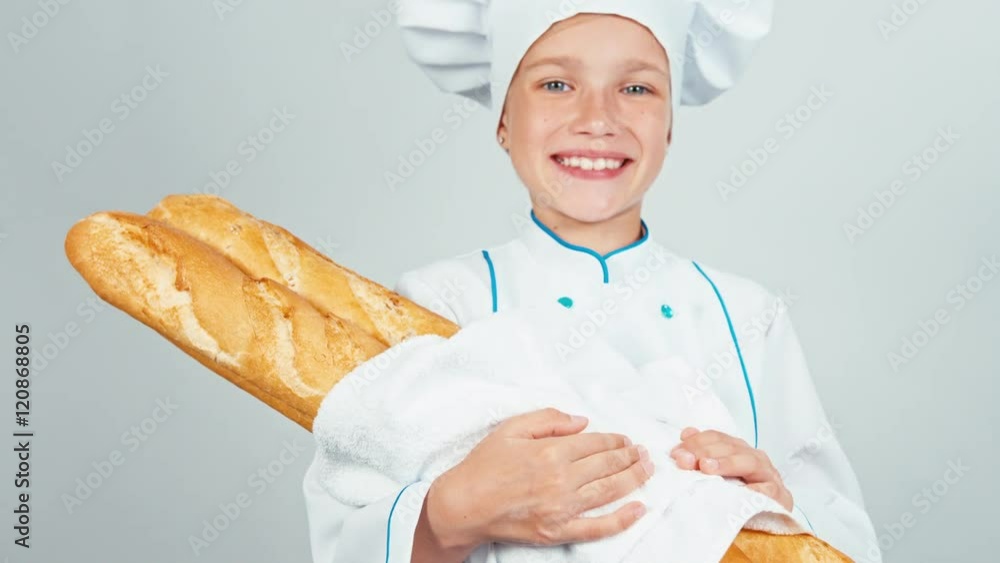 Portrait young baker girl 7-8 years holds long loaves and smiling at camera isolated on white background. Thumb up. ok Portrait young baker girl 7-8 years holds long loaves and smiling at camera isolated on white background. Thumb up. ok