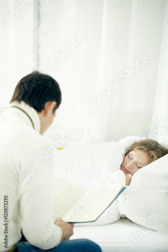 Man reading for his ill wife to sleep