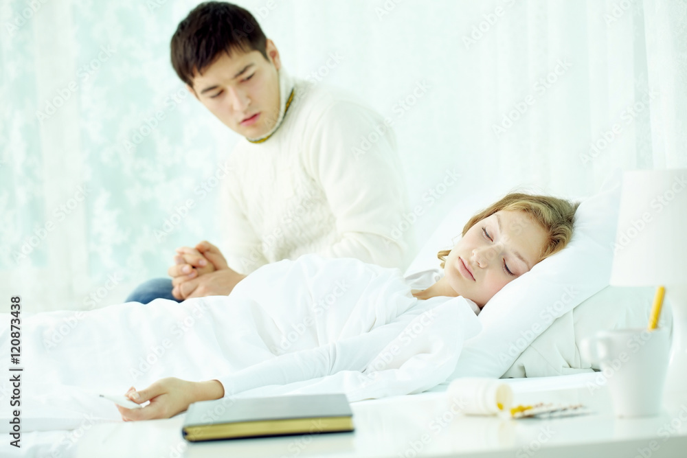 Fototapeta premium Man looking anxiously at his wife that fell asleep with fever