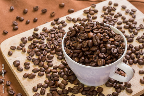 Coffee Cup with coffee beans on wood of coffee beans background.