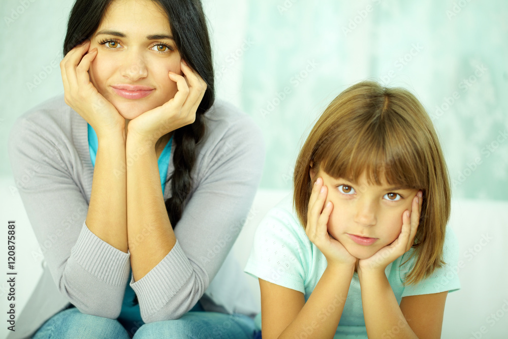 Portrait of mother and daughter looking at camera with hands on cheeks Portrait of mother and daughter looking at camera with hands on cheeks