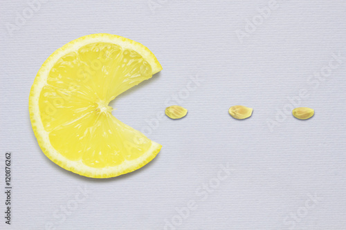 Yum-yum / Creative concept photo of a lemon slice eating seeds on grey background.
