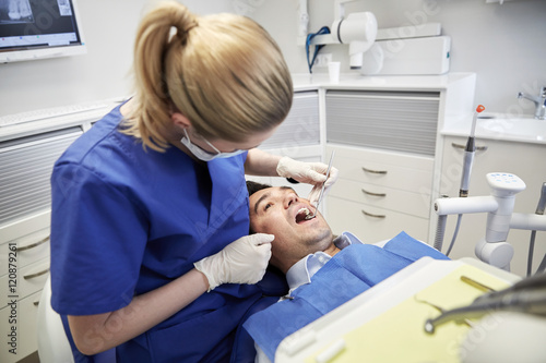 female dentist checking up male patient teeth