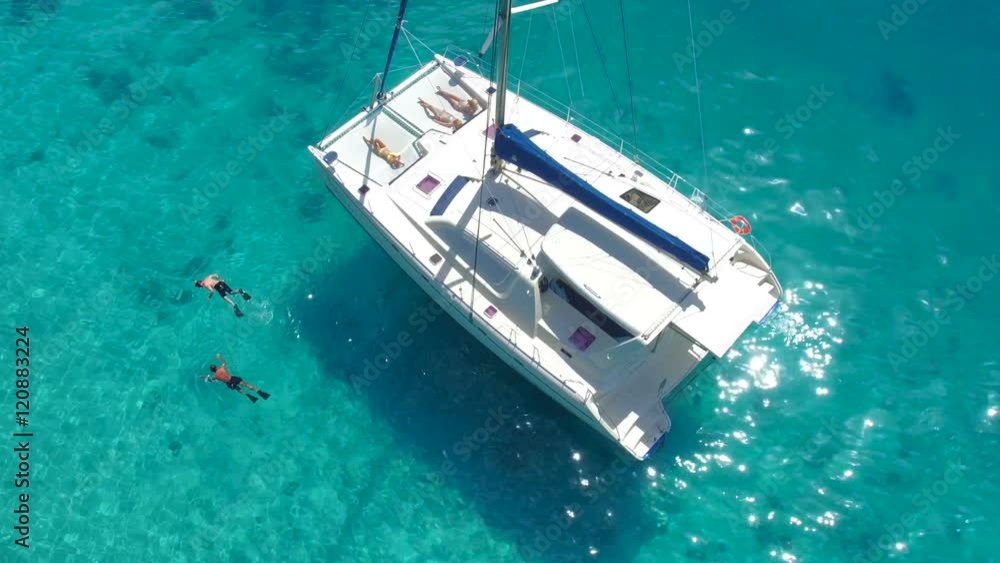 Aerial video of a group of people relaxing and snorkeling on a catamaran in the Caribbean Aerial video of a group of people relaxing and snorkeling on a catamaran in the Caribbean