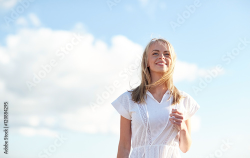 smiling young woman in white dress over blue sky