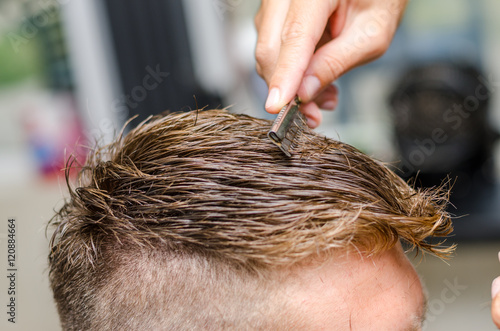 Hairdresser cutting man's hair with toothed razor