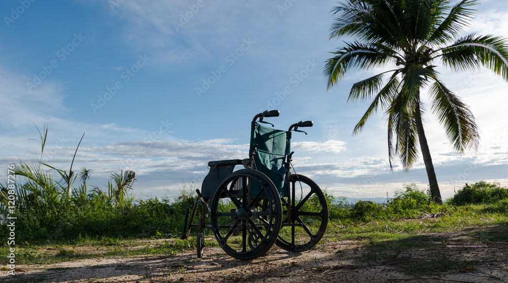 Fototapeta premium Empty wheelchair on the lake at sunset.