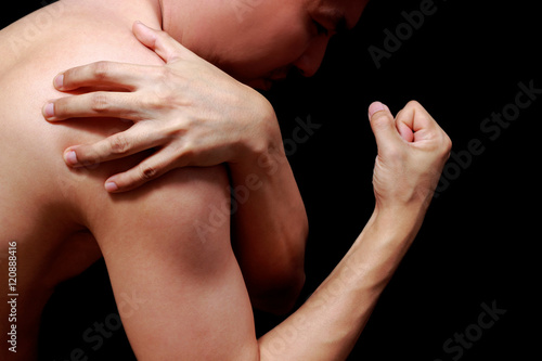 asian man showing his muscle in pain  isolated on black