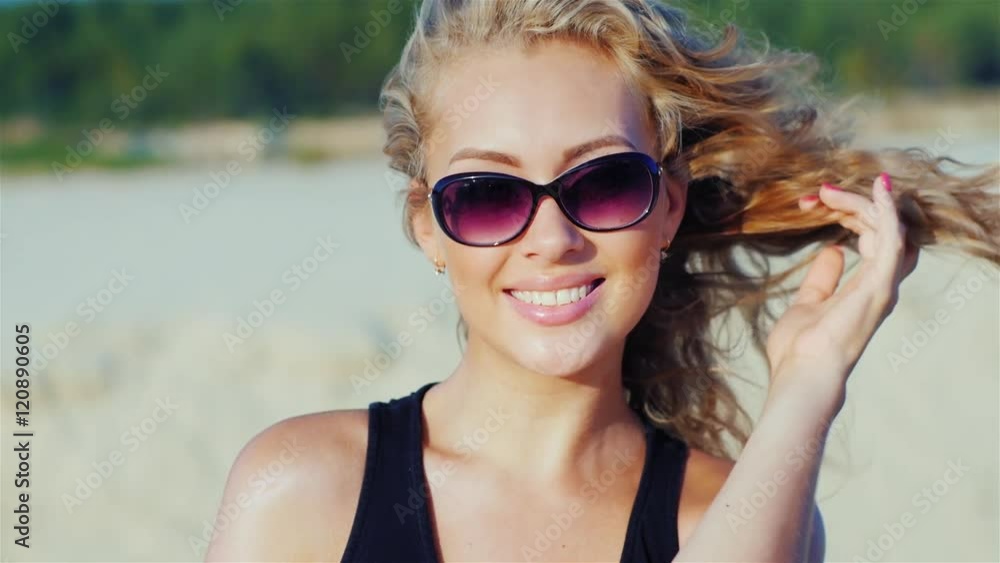 Portrait of a young attractive woman smiling, looking into the camera, posing on the beach Portrait of a young attractive woman smiling, looking into the camera, posing on the beach