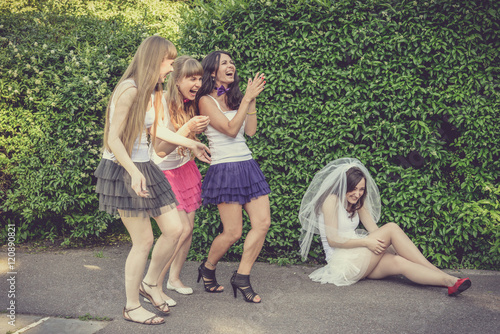 Beautiful bride and happy bridesmaids celebrating hen-party.Happy young hipster girls having fun at bridal shower, wearing colorful fluffy skirts and white t-shirt outdoors in city park on a sunny day photo