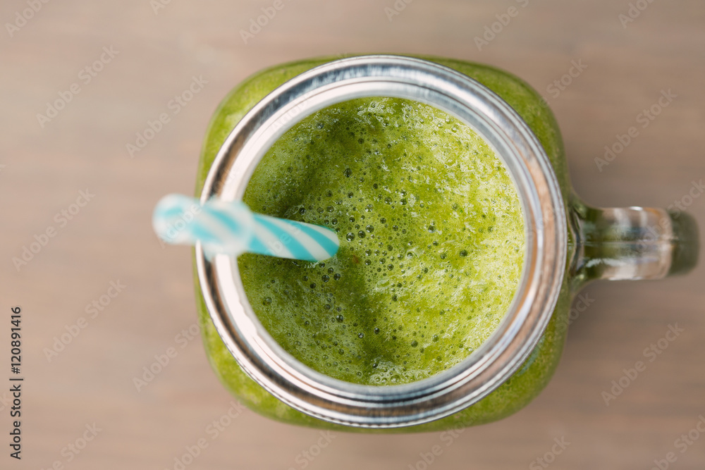 A green smoothie in a mason jar on wooden background A green smoothie in a mason jar on wooden background