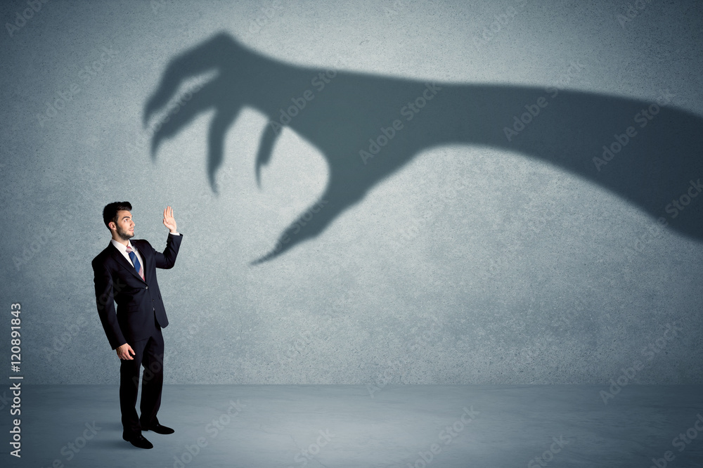 Business person afraid of a big monster claw shadow concept Business person afraid of a big monster claw shadow concept