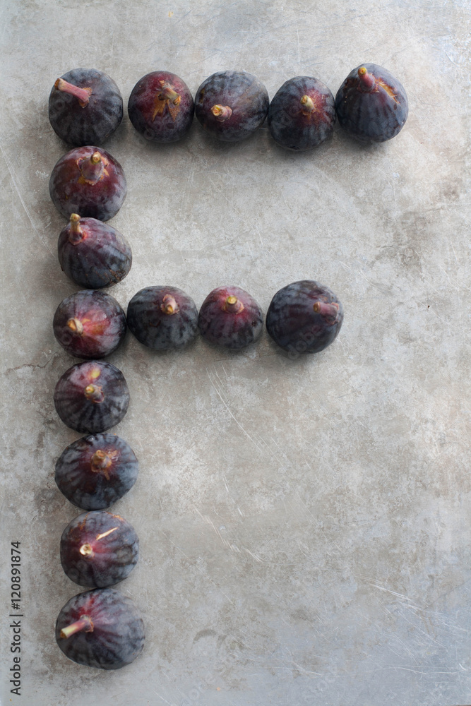 Capital letter F out of fresh figs, gray background Capital letter F out of fresh figs, gray background