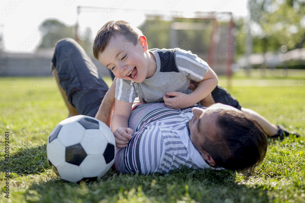 man with child playing football on field