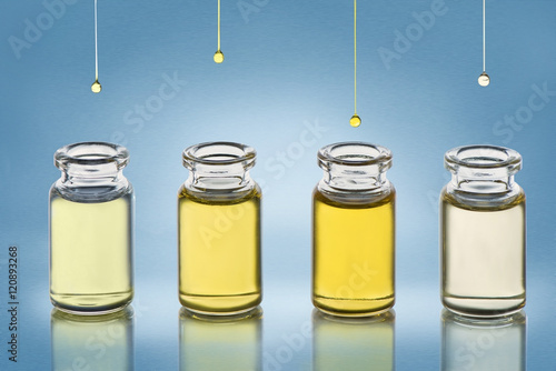 Four bottle with different cosmetics oil stand on the blue gradient metallic texture background