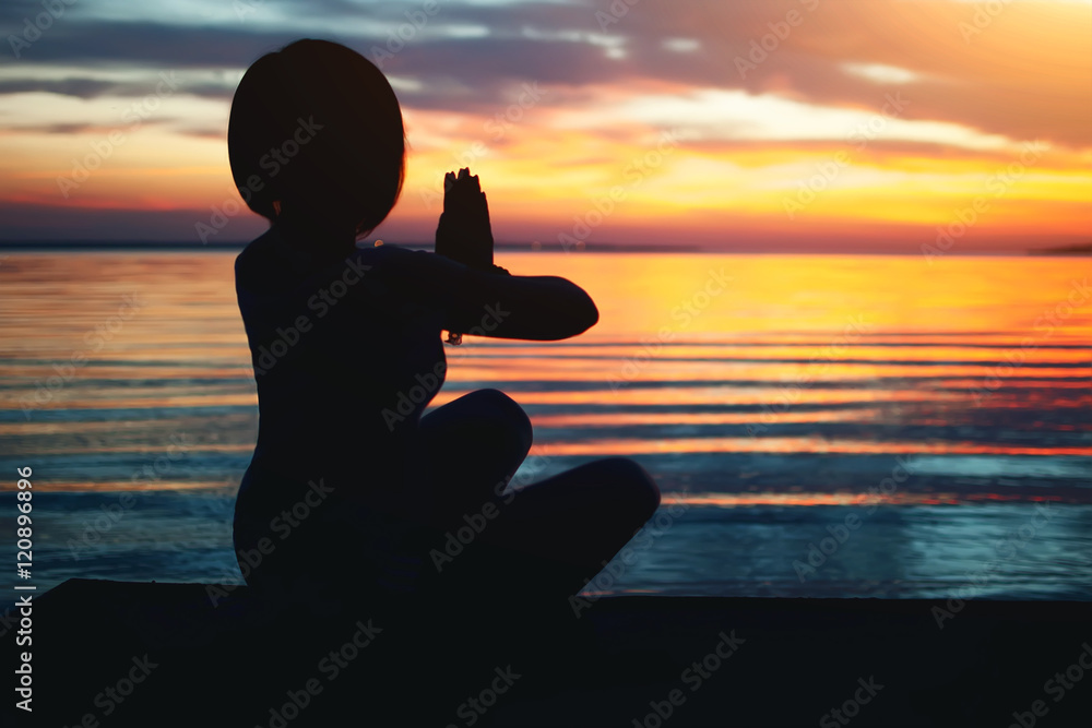 woman doing yoga in ocean beach on sunset