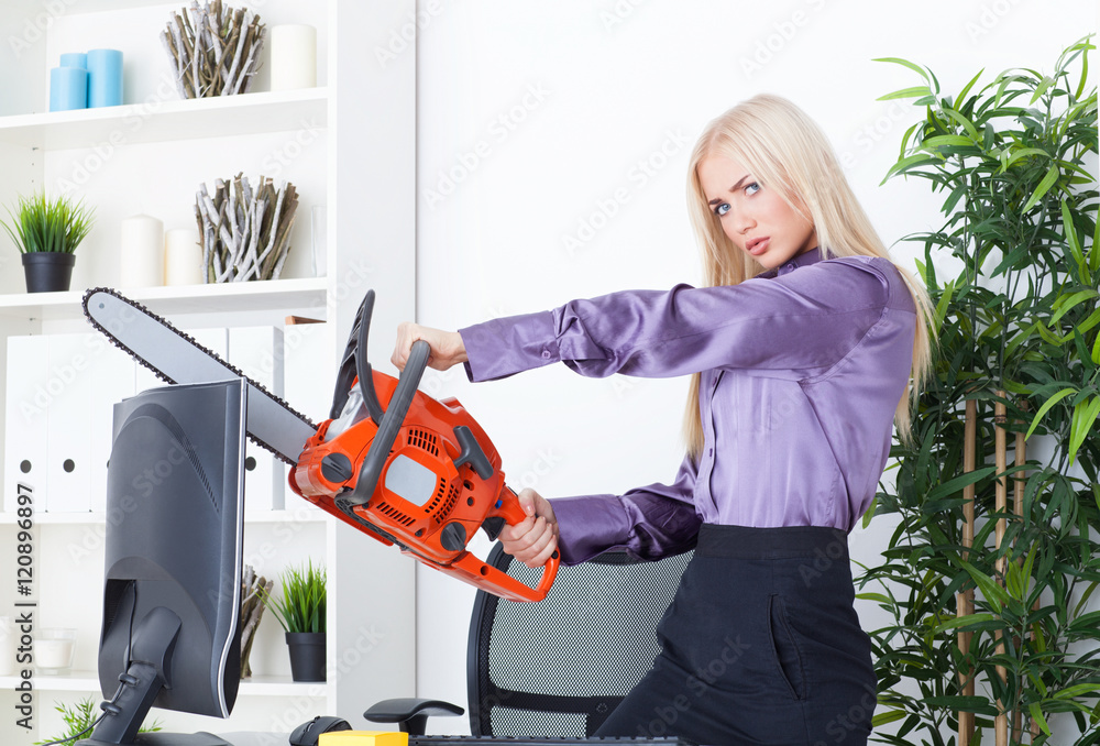beautiful girl at the office cuts the monitor with a chainsaw beautiful girl at the office cuts the monitor with a chainsaw