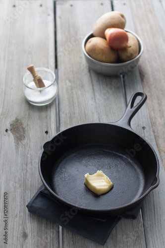 cast iron skillet with butter, weathered wood table 