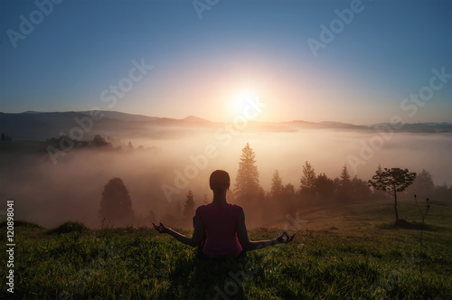 young woman doing yoga fitness in nature with ountain view on sunset