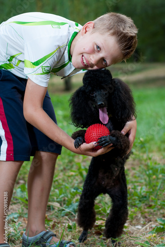 boy with a black poodle on nature