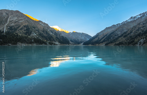 the water surface of a mountain lake, mountains reflected in the water, the water turquoise,summer
