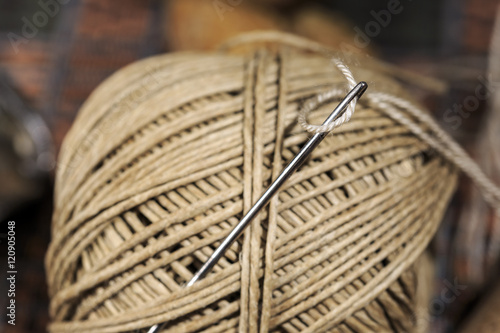 Leather needle skewered on spool of waxed hemp thread. Shoemaker's tools photo