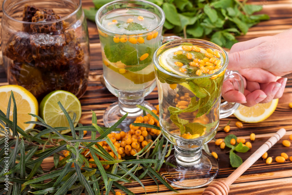 Cup of tea with sea buckthorn, lemon, lime, honey and mint. Autumn, winter beverage concept. Cup of tea with sea buckthorn, lemon, lime, honey and mint. Autumn, winter beverage concept.