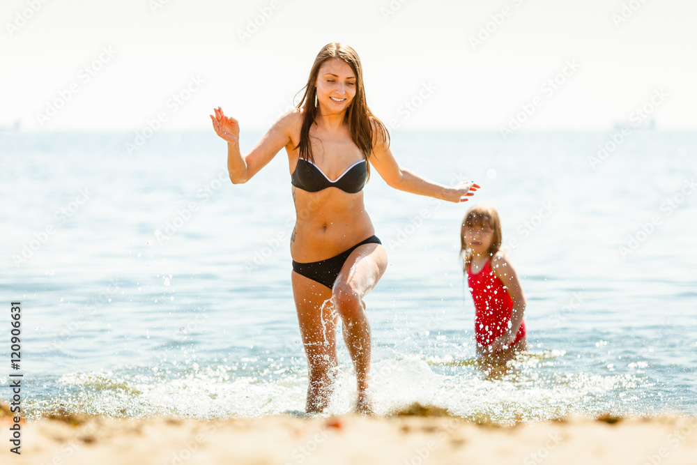 Little girl kid and woman mother in sea water. Fun