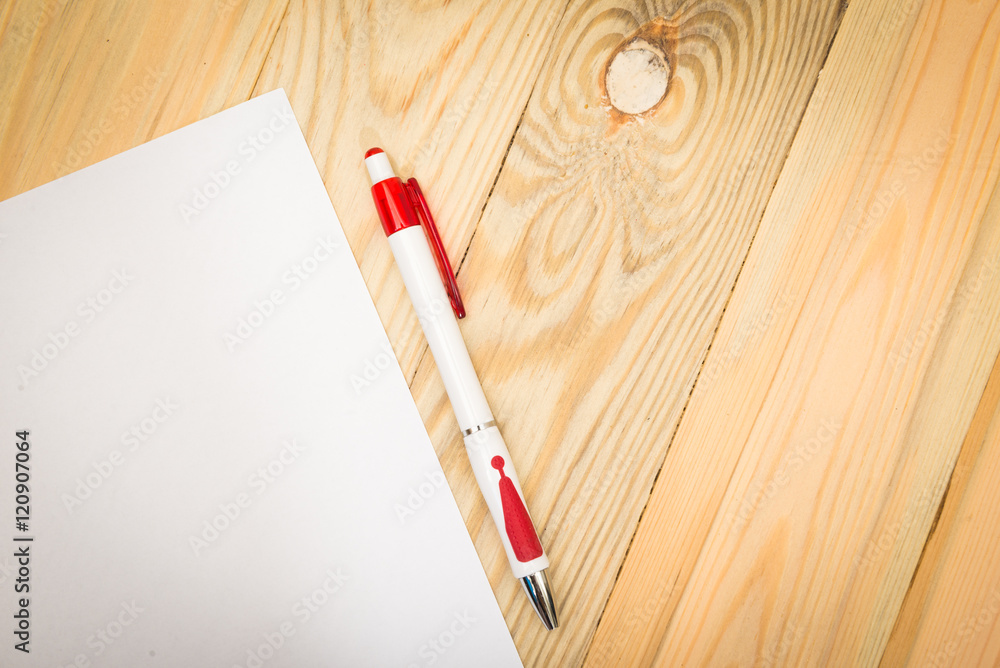 Obraz premium Blank white paper with pen on a wooden desk.