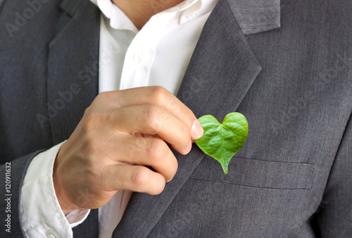 Businessman holding a green heart leaf / Business with corporate social responsibility and environmental concern photo