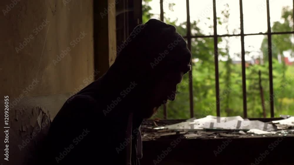 Man sitting nex to the bars in darkness and looking morose, steadycam shot
Man sitting nex to the bars in darkness and looking morose, steadycam shot